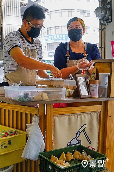 清新和風木作小攤車後方，藍淯柔正熟練地捏出一顆顆圓滾飽滿的麻糬，再由先生接手，包裝成可愛的三角飯糰形狀，兩人合作無間。